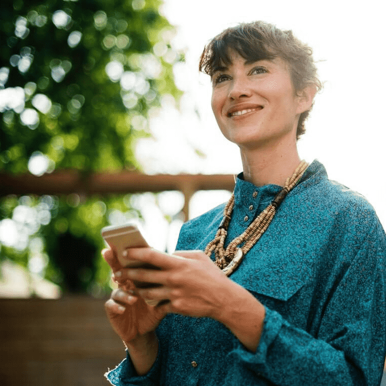 Woman beaming with joy while chatting with AI on her phone